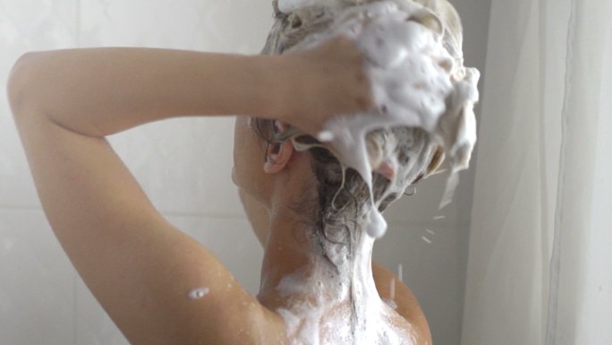 一名女子正使用洗发水洗头发
