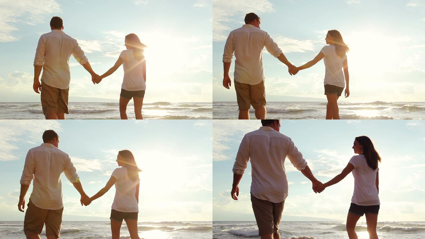 年轻夫妇手牵着手在日落时分的海滩上散步