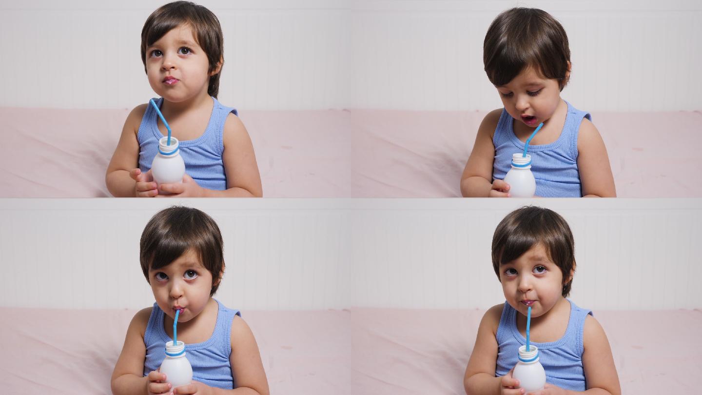 穿着蓝色t恤的男婴坐着喝牛奶