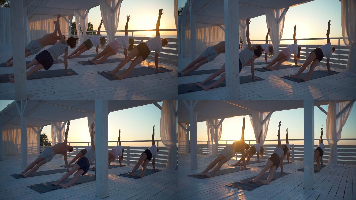 年轻人们在黎明的露台上练习瑜伽