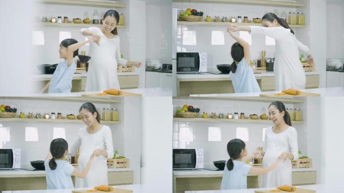 孕妇和她的女儿在家里做饭跳舞。