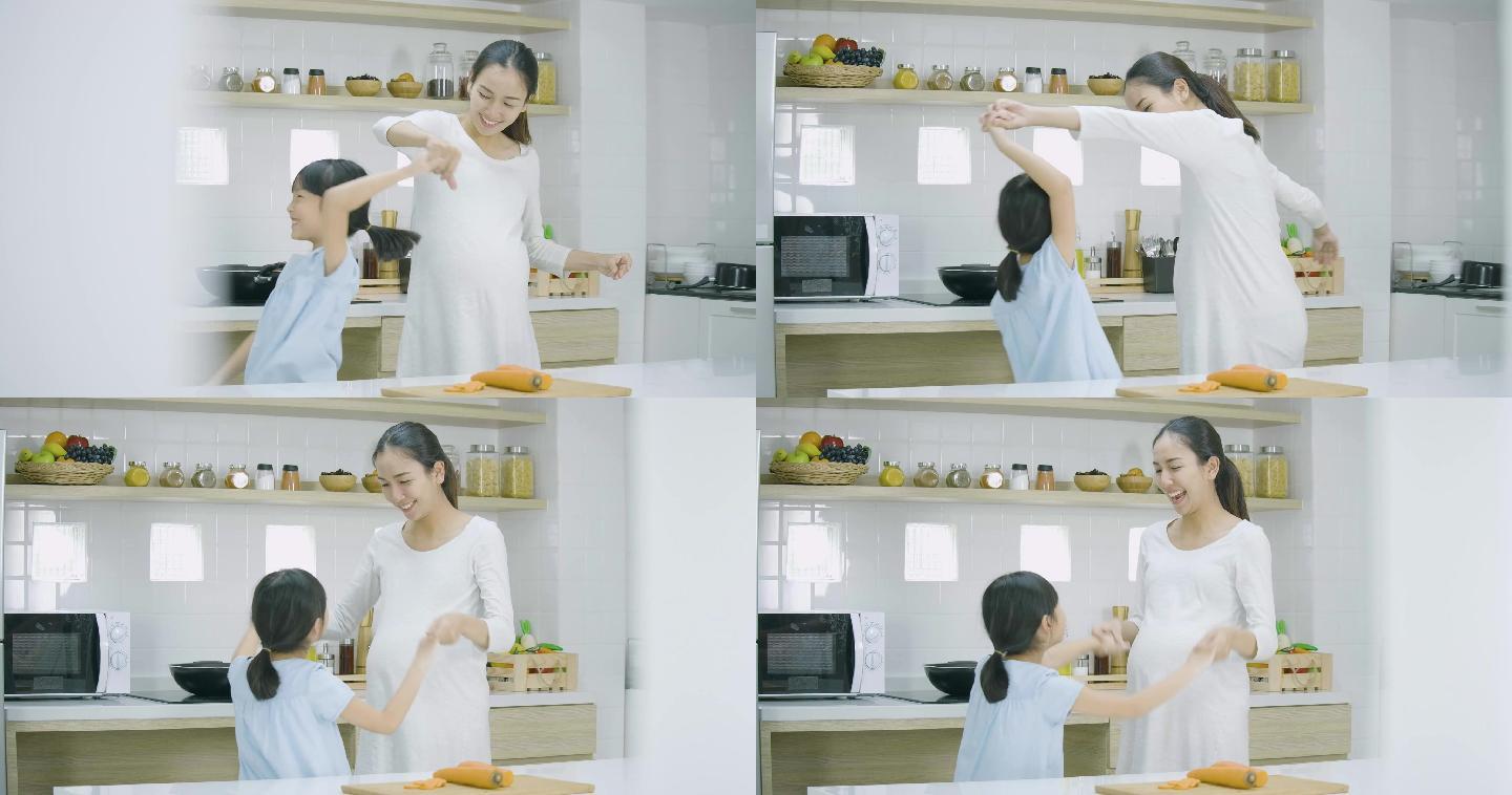孕妇和她的女儿在家里做饭跳舞。