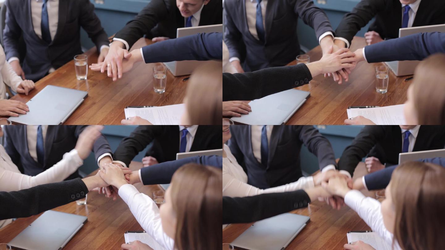 一个团队在会议中将手叠起加油打气