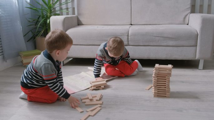 双胞胎男孩在地上搭积木