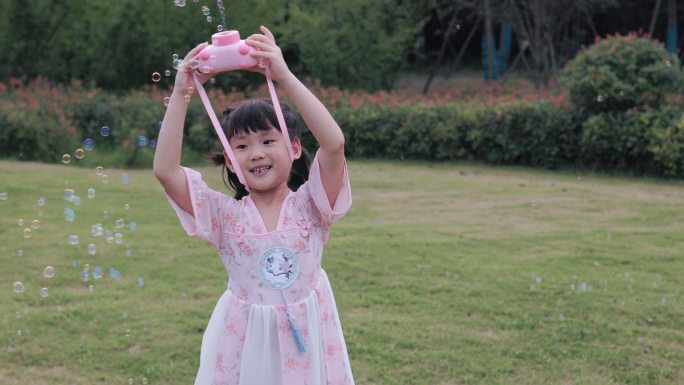 4K公园草坪上玩泡泡机的小女孩