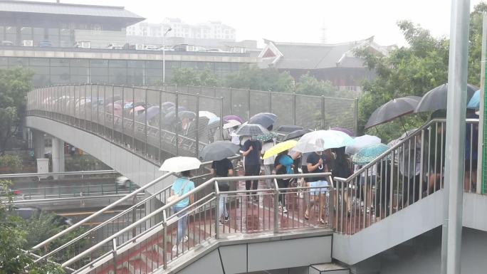 大暴雨行人打雨伞地铁过天桥上班