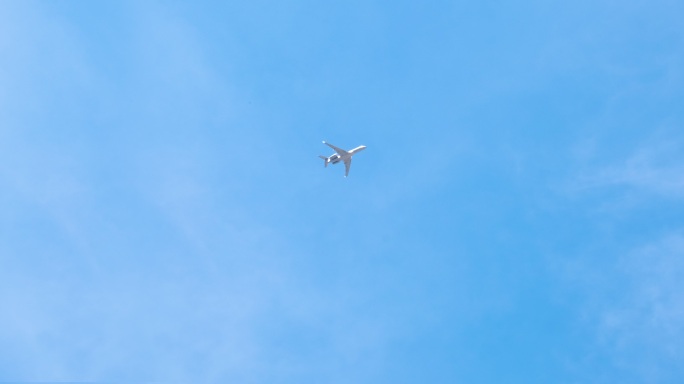 白色的飞机在蓝天上飞行。底视图