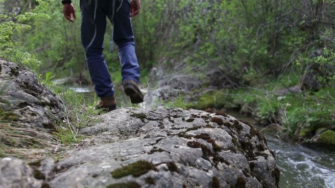 探险家走在河边的一条岩石小道上