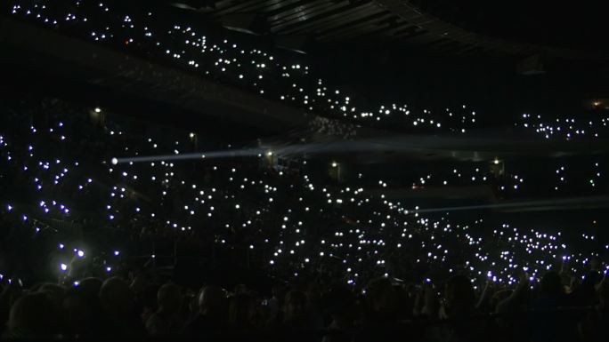 夜间体育场看台上打开照明灯的一群人