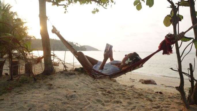 在海边吊床上看书的漂亮女人
