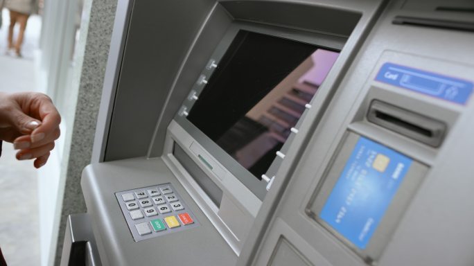 女性将银行卡插入ATM查询余额