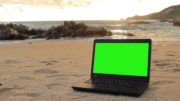 海滩上的绿色屏幕笔记本电脑