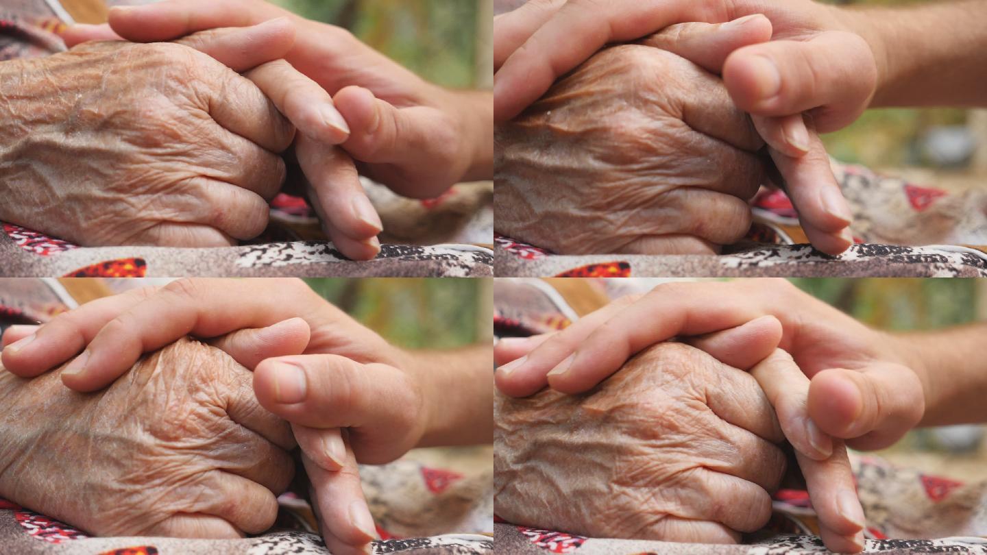 年轻男性的手抚慰老年女性的手的特写镜头。
