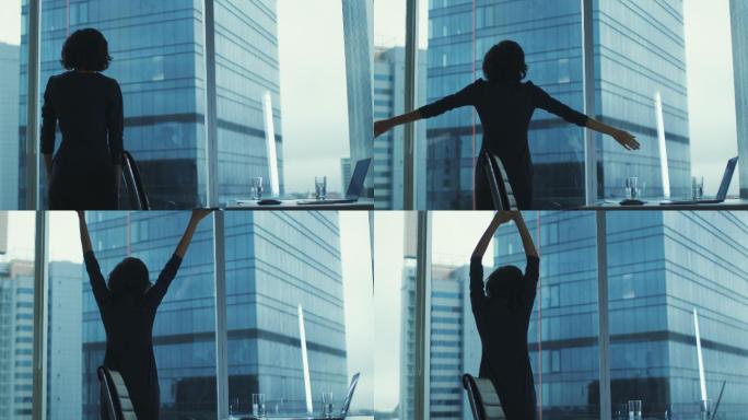 女人站在办公室伸懒腰时从窗外看城市风景。