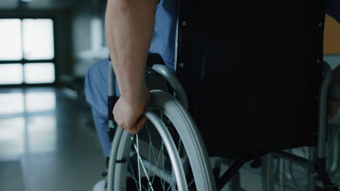 在医院里，一位坐轮椅的老人穿过走廊