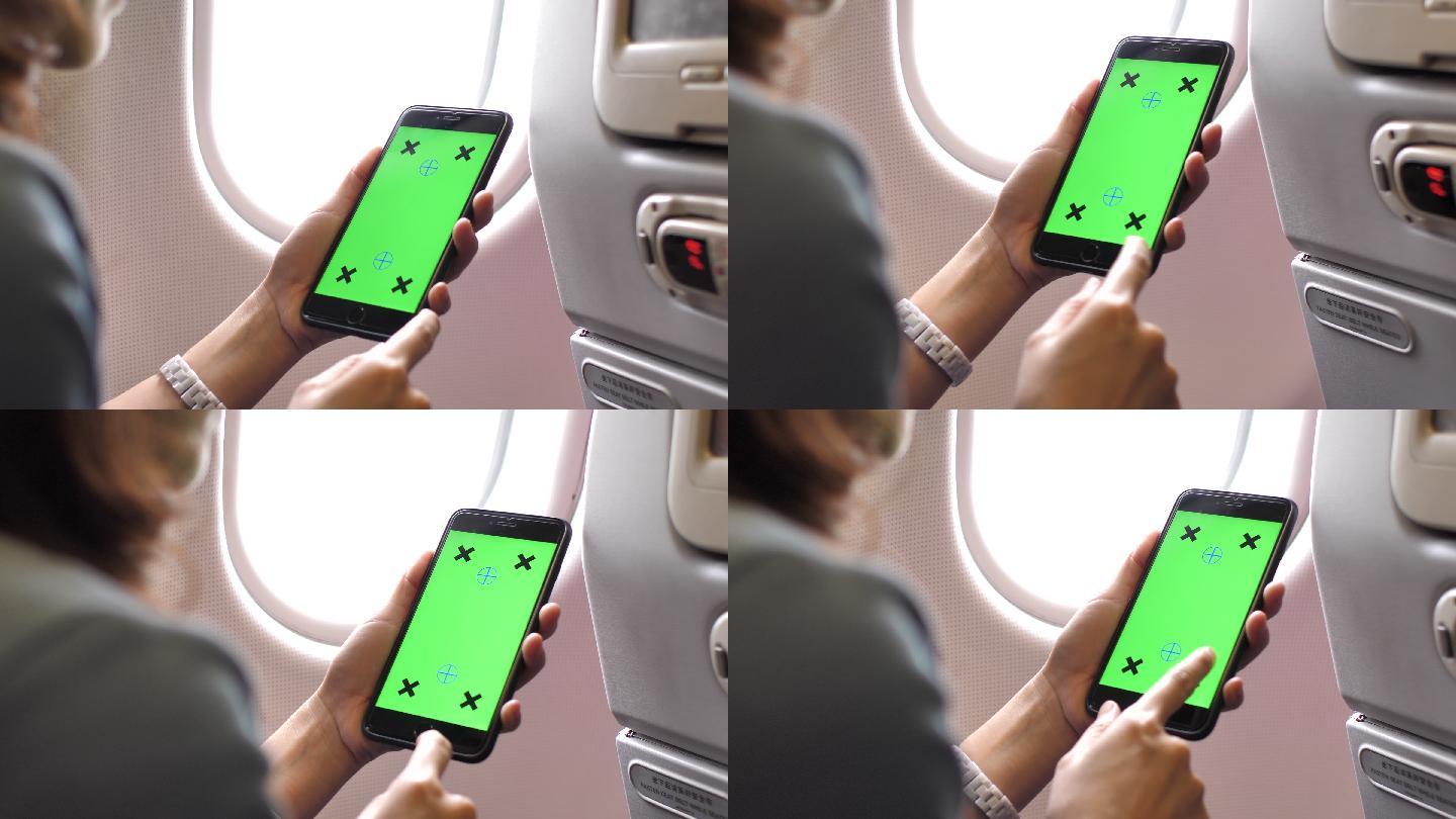 女乘客在飞机上使用绿色屏幕智能手机