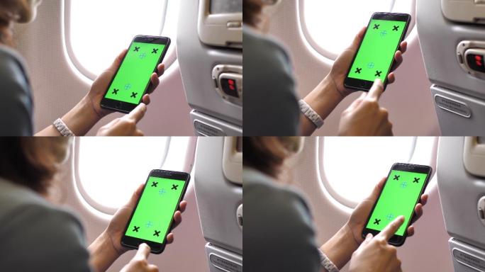 女乘客在飞机上使用绿色屏幕智能手机