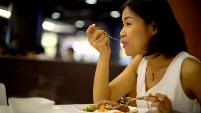 美丽的女人在餐馆里吃猪肉和米饭