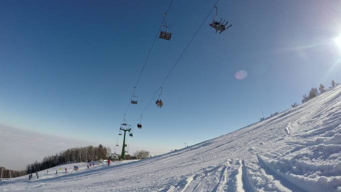在滑雪坡上，滑雪者在滑雪升降椅下滑雪。