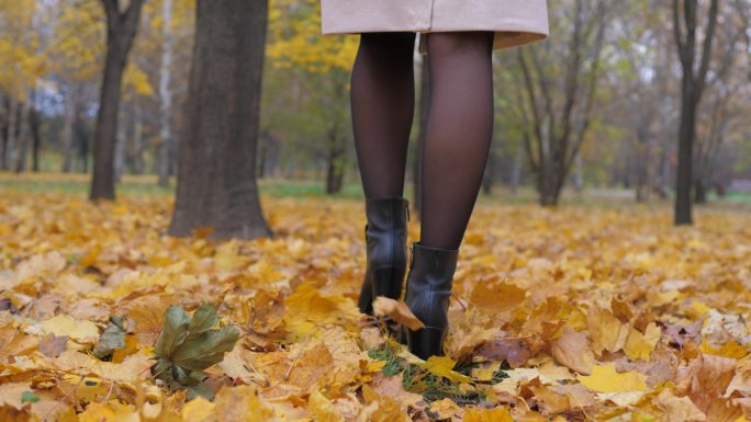 女人在满是黄色落叶的树林里行走