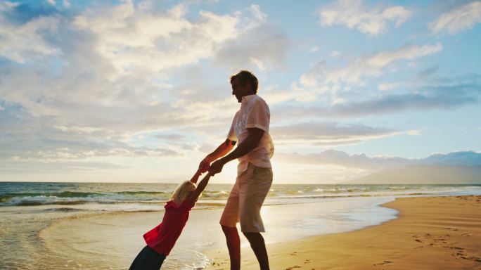 父亲和儿子在日落时在海滩上玩耍