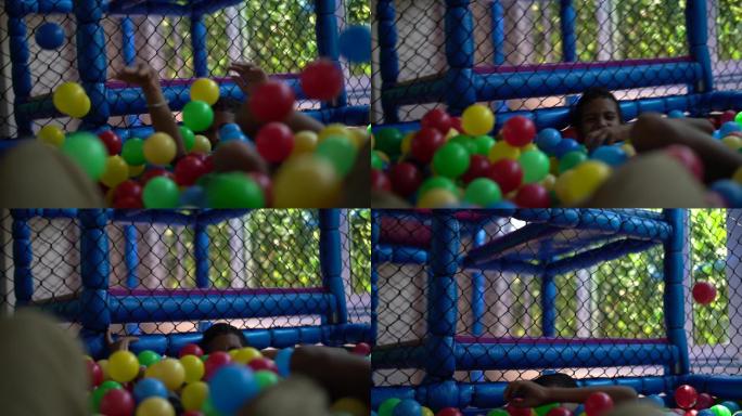 男孩在塑料池里玩五颜六色的球
