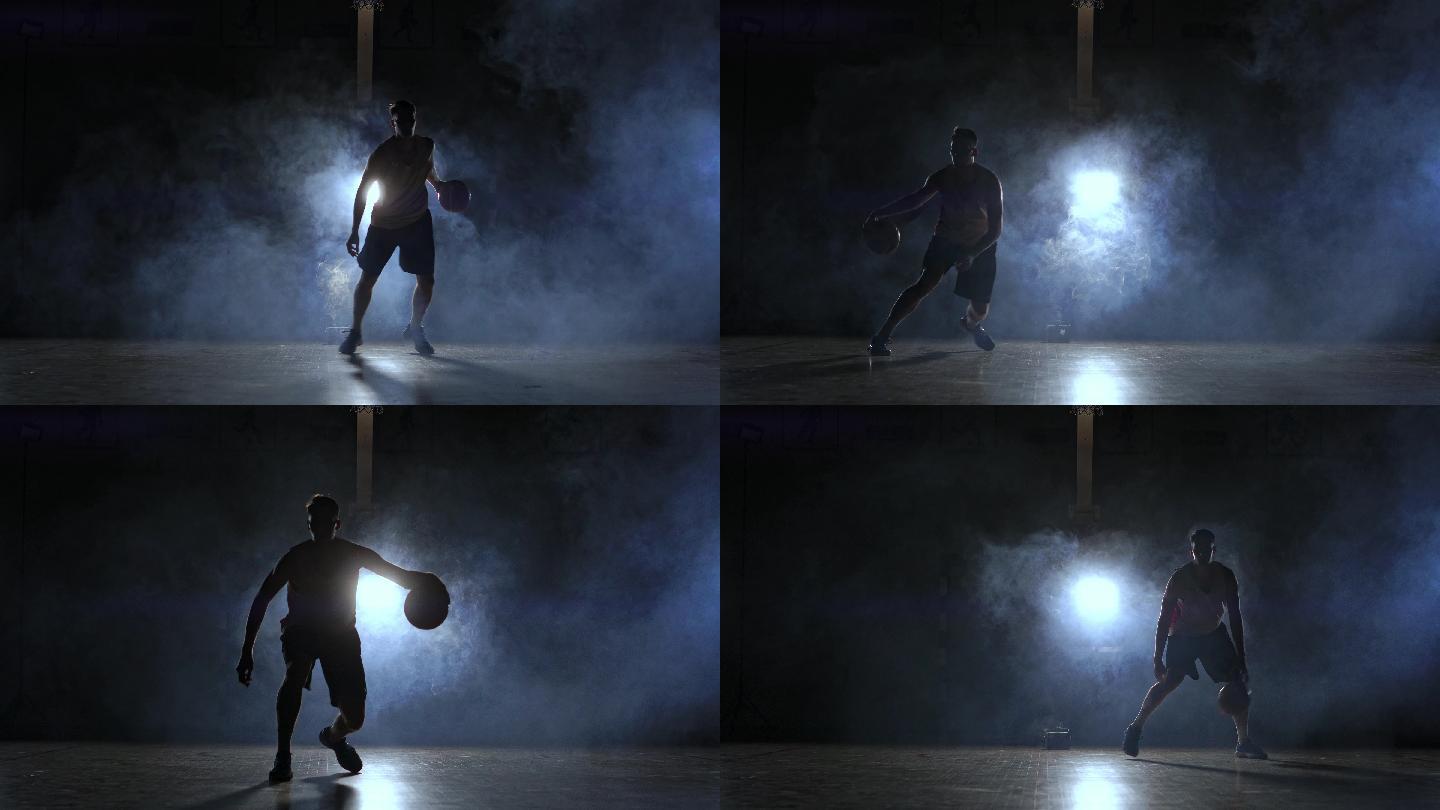 一名男子拿着一个篮球站在黑暗的篮球场上