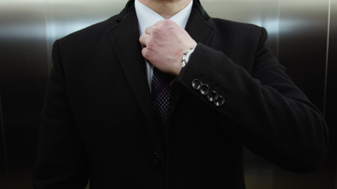 商人在电梯里拉直了领带