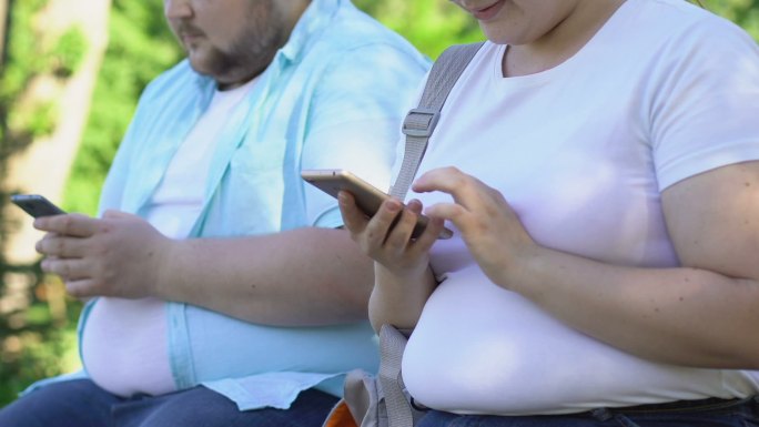 两名年轻人在公园使用智能手机