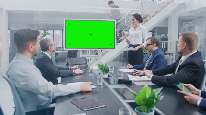 在会议室女高管使用绿色屏幕向同事展示内容