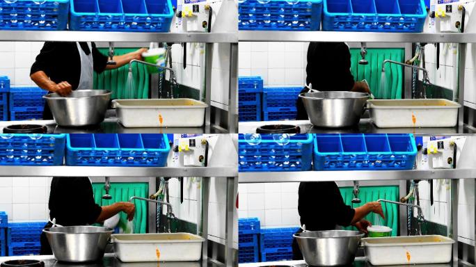 一名男子在一家商业厨房里洗餐具