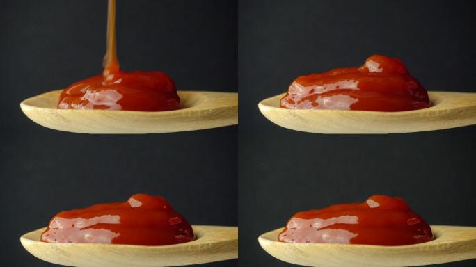 红色番茄酱落在勺子里，背景为黑色