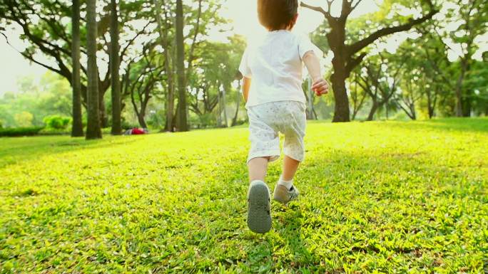小男孩在公园里奔跑，背景是日落