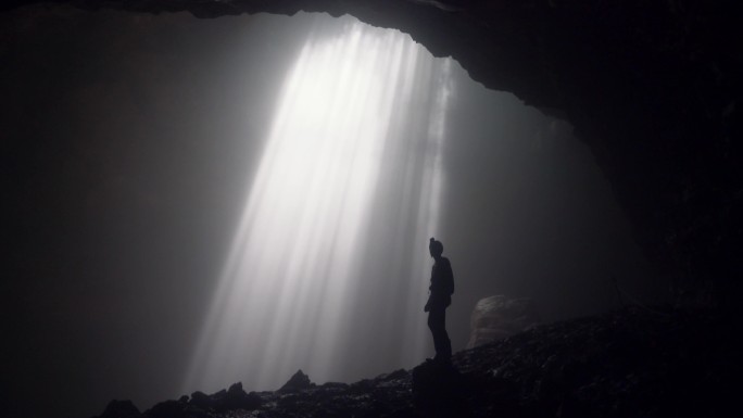 在阳光下站在洞穴中的男人