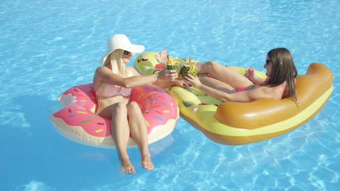 两名女子躺在游泳圈上喝酒晒太阳