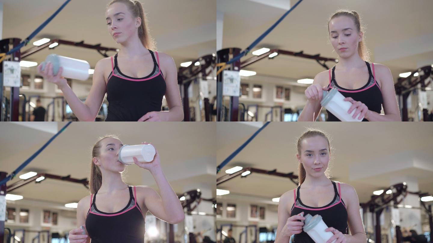 迷人的女孩在健身房喝蛋白质奶昔