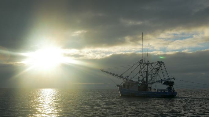 捕鱼船在日出时用网捕鱼