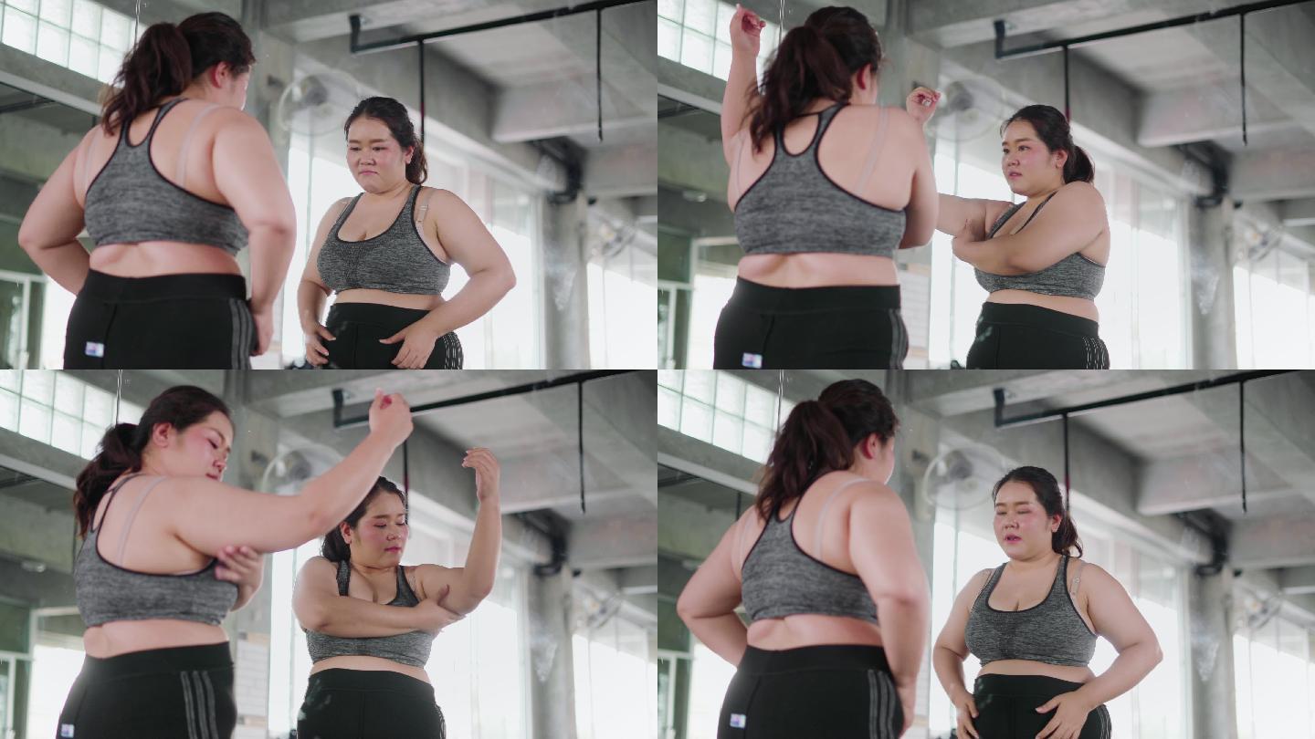 一个超重的女人在健身房照镜子。