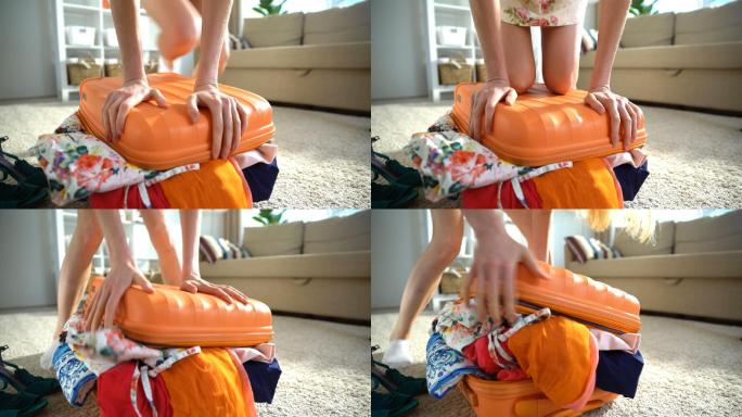 女子正试图合上一个塞满衣服的行李箱