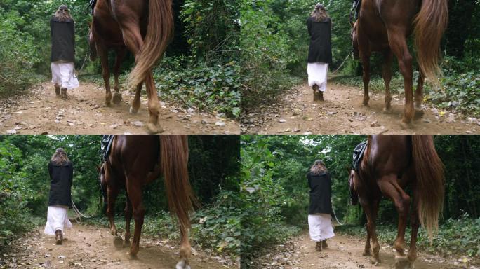 一个年轻女子在森林里牵着她的马行走