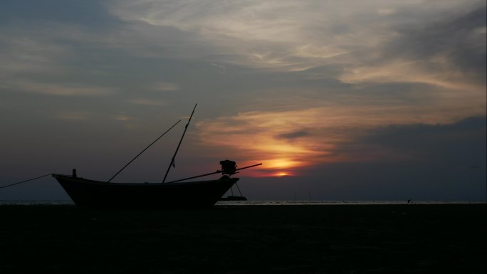 海滩夕阳天空下的渔船剪影延时