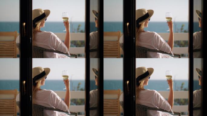 在阳台放松的女人一边喝酒一边欣赏海景