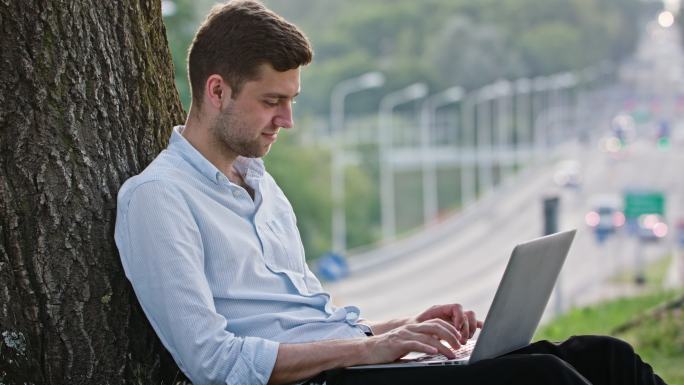 在室外使用笔记本电脑的男人