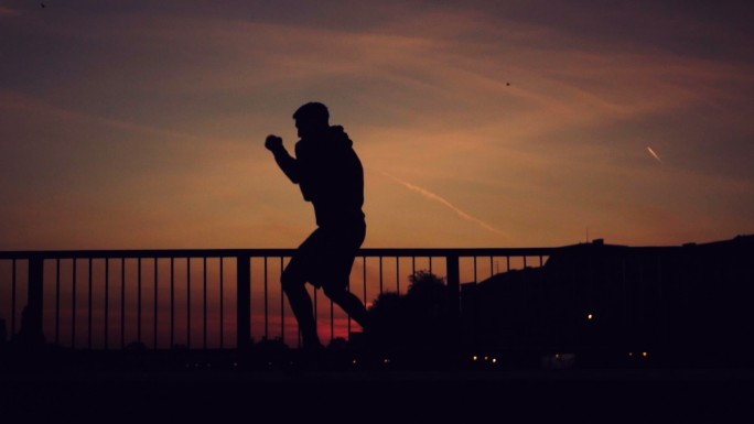 强壮而肌肉发达的拳击手在日落时打拳。