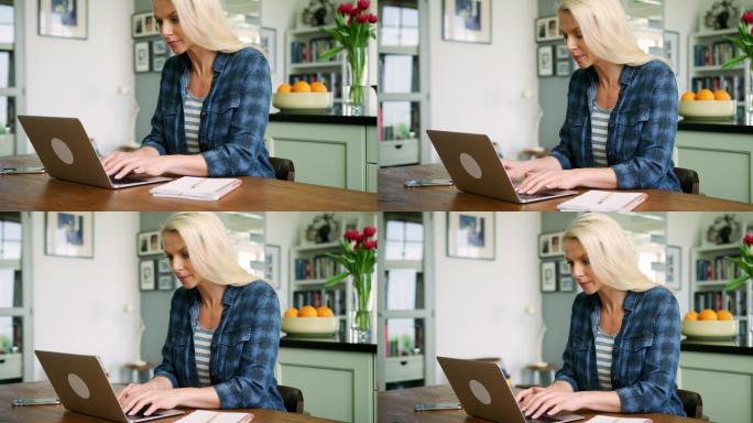 金发女人在餐桌旁用笔记本电脑打字