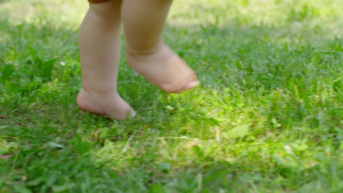 赤脚在草地上行走的婴儿的腿