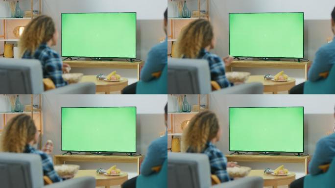 夫妇坐在家里的客厅里，看着绿色的彩色键屏幕电视