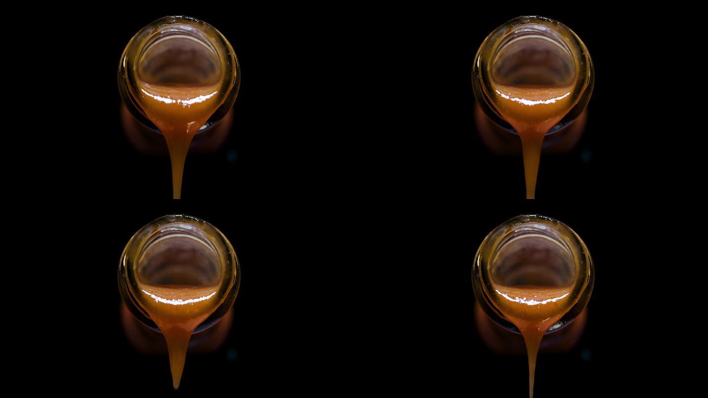 辣椒酱从一个玻璃瓶倒出的前视图，黑色背景