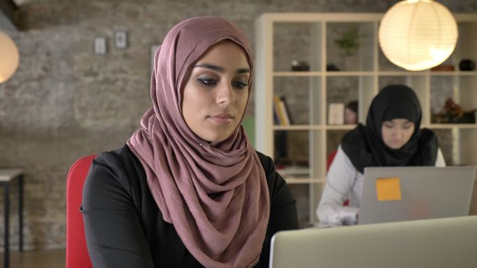 在现代办公室里年轻的穆斯林妇女在工作。