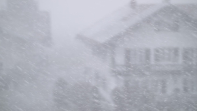 雪花飘落在房屋模糊的景色前。